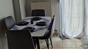 Ein Essbereich mit einem Tisch für vier Personen, Stühlen, einem Heizkörper und einem Fenster mit Vorhängen.