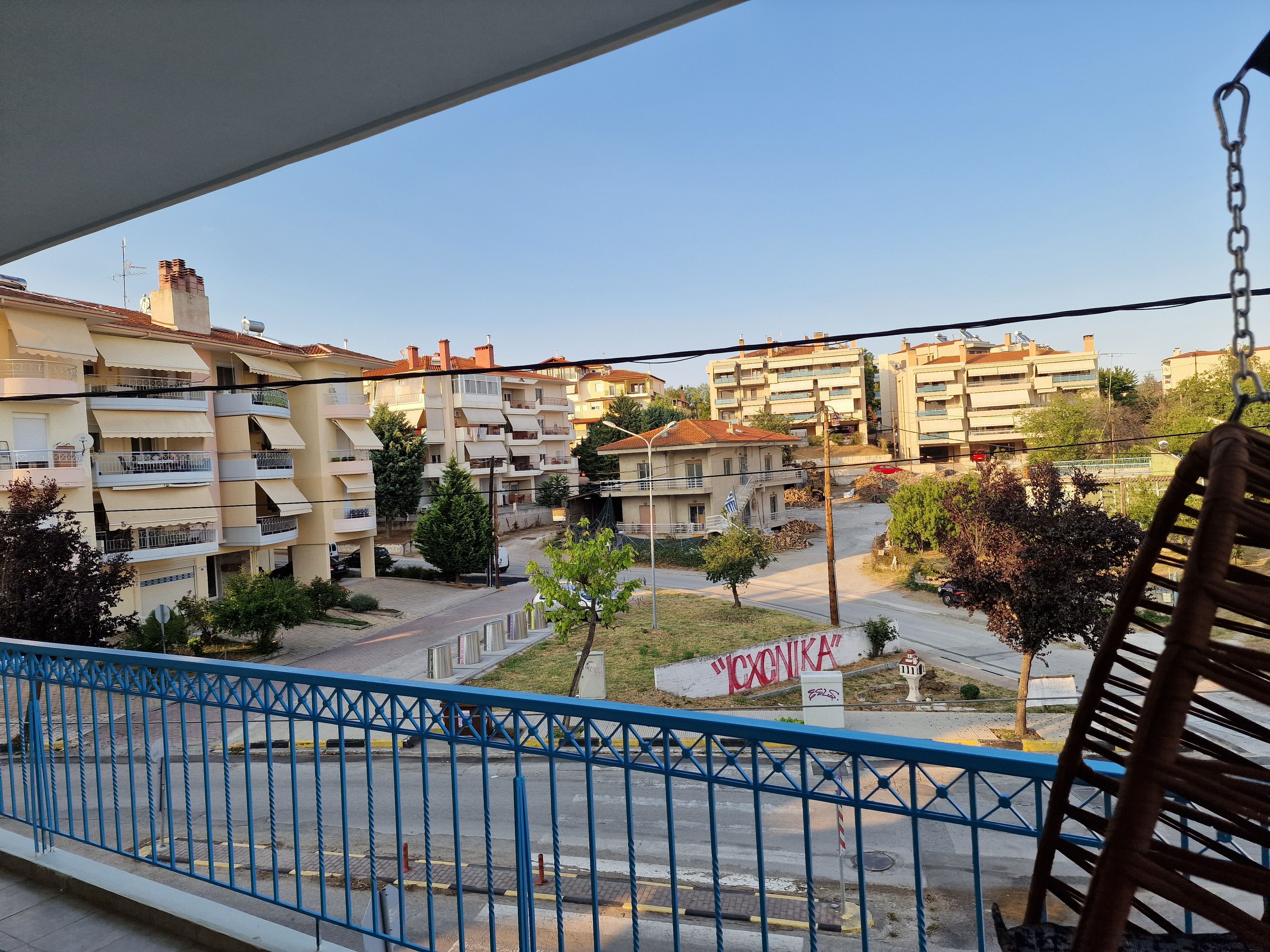 Un balcone con vista su edifici residenziali, una strada e un cartello con del testo.