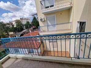 A residential building with a red-tiled roof, a blue metal railing, and a white door.