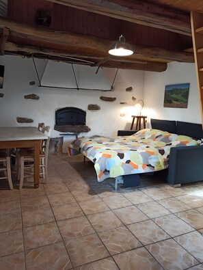Een slaapkamer met een bed, een tafel, stoelen, een open haard en een schilderij aan de muur.