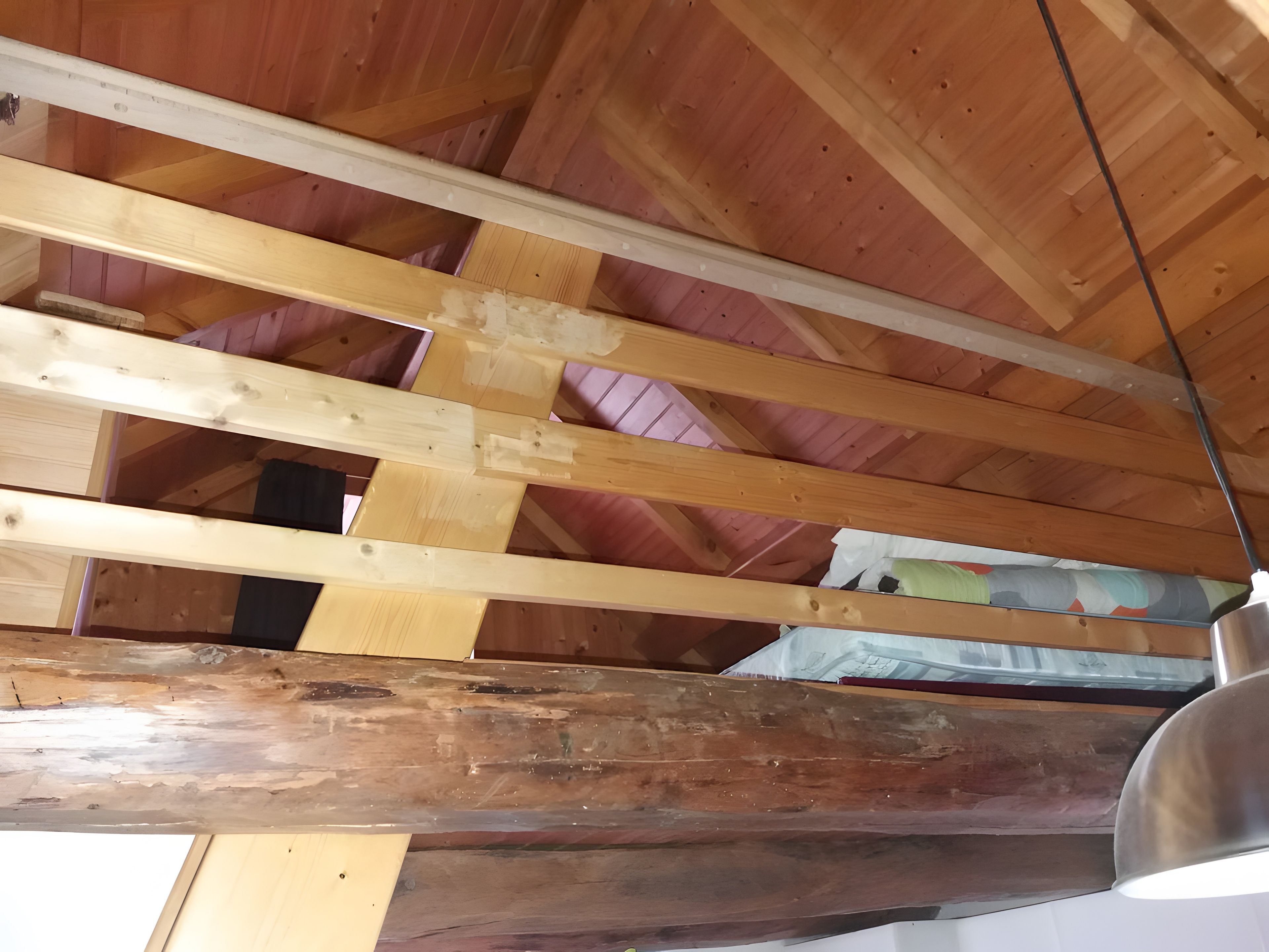 Estructura de techo de madera con vigas visibles y aislamiento.