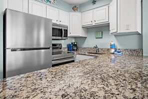 A modern kitchen with stainless steel appliances, granite countertops, and white cabinetry. - 🌴Stunning Gulf Views | Pool | Jetty East 117A🌴 (Destin)