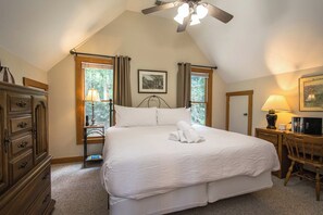A bedroom with a large bed, a ceiling fan, a desk with a lamp, and a window with curtains. - Lake Lure Area Retreat with Hot Tub and Game Room (Rutherfordton)