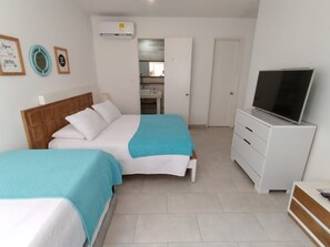 A bedroom with two beds, a TV, a wardrobe, and a bathroom visible through an open door. - Inspiration from the Sea (Cartagena)