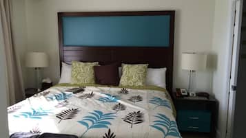 Een hotelkamer met een groot bed, twee nachtkastjes, een koffer en een deur.