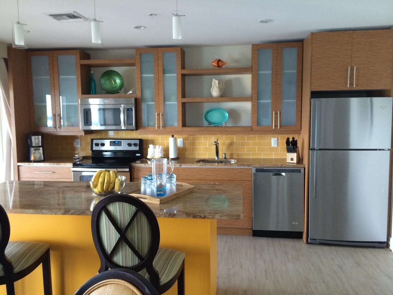 Een moderne keuken met een centraal eiland, roestvrijstalen apparatuur en houten keukenkastjes.
