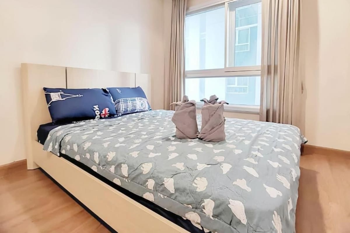 A neatly made bed with a patterned bedspread, a headboard, and two pillows.