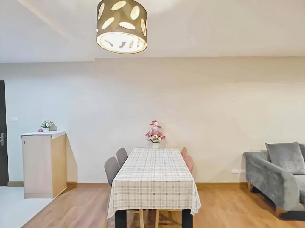 A dining area with a table, chairs, a vase with flowers, and a sofa.