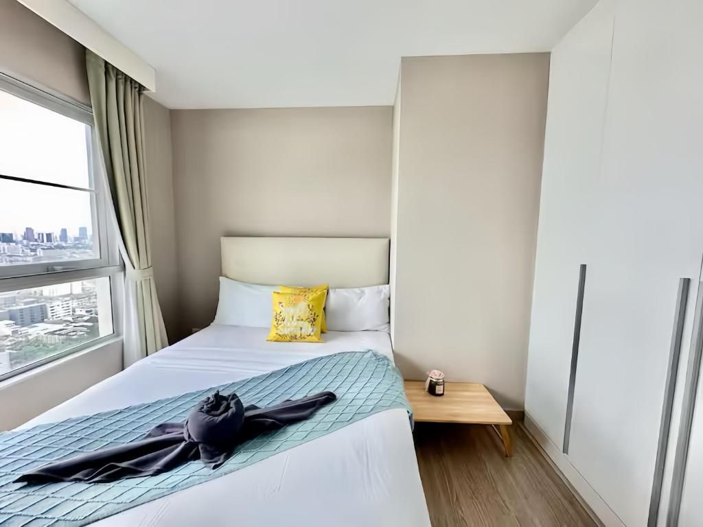 A hotel room with a bed, a nightstand, a window with curtains, and a city view.