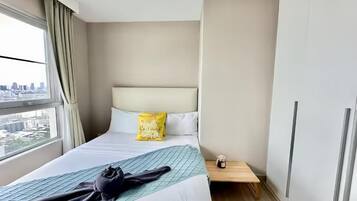 A hotel room with a bed, a nightstand, a window with curtains, and a city view.
