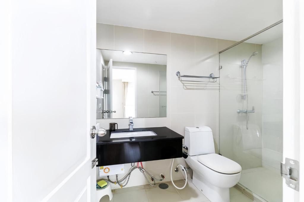 A bathroom with a white toilet, a black sink, and a glass-enclosed shower area.