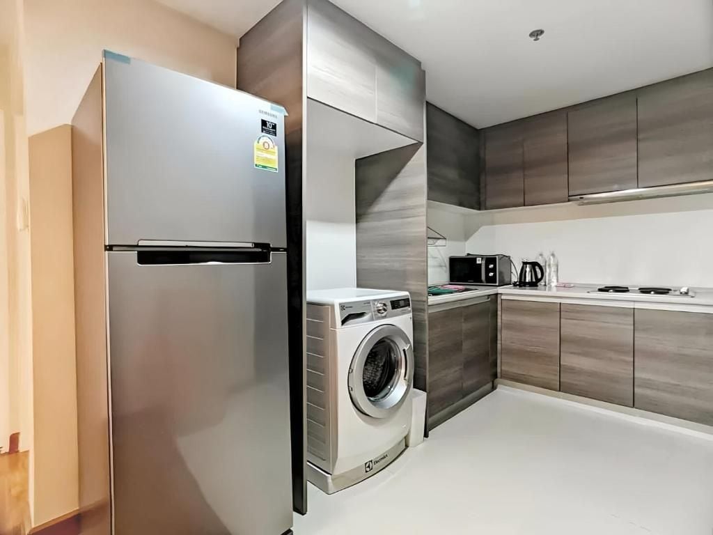 Una cocina moderna con lavadora incorporada, refrigerador de acero inoxidable y microondas.