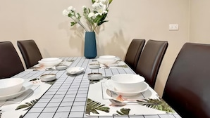 A dining table set with plates, bowls, and a vase of flowers. - Belle Grand Rama 9 Bangkok (Krung Thep Maha Nakhon)
