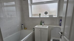 Un baño pequeño con bañera, lavamanos e inodoro.
