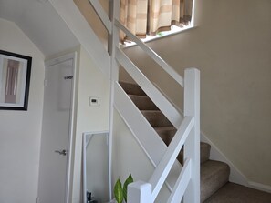 Eine Treppe mit weißen Geländern und Teppichstufen, die zu einer oberen Etage führt.