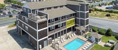 A multi-story building with a rooftop pool and a view of the ocean.