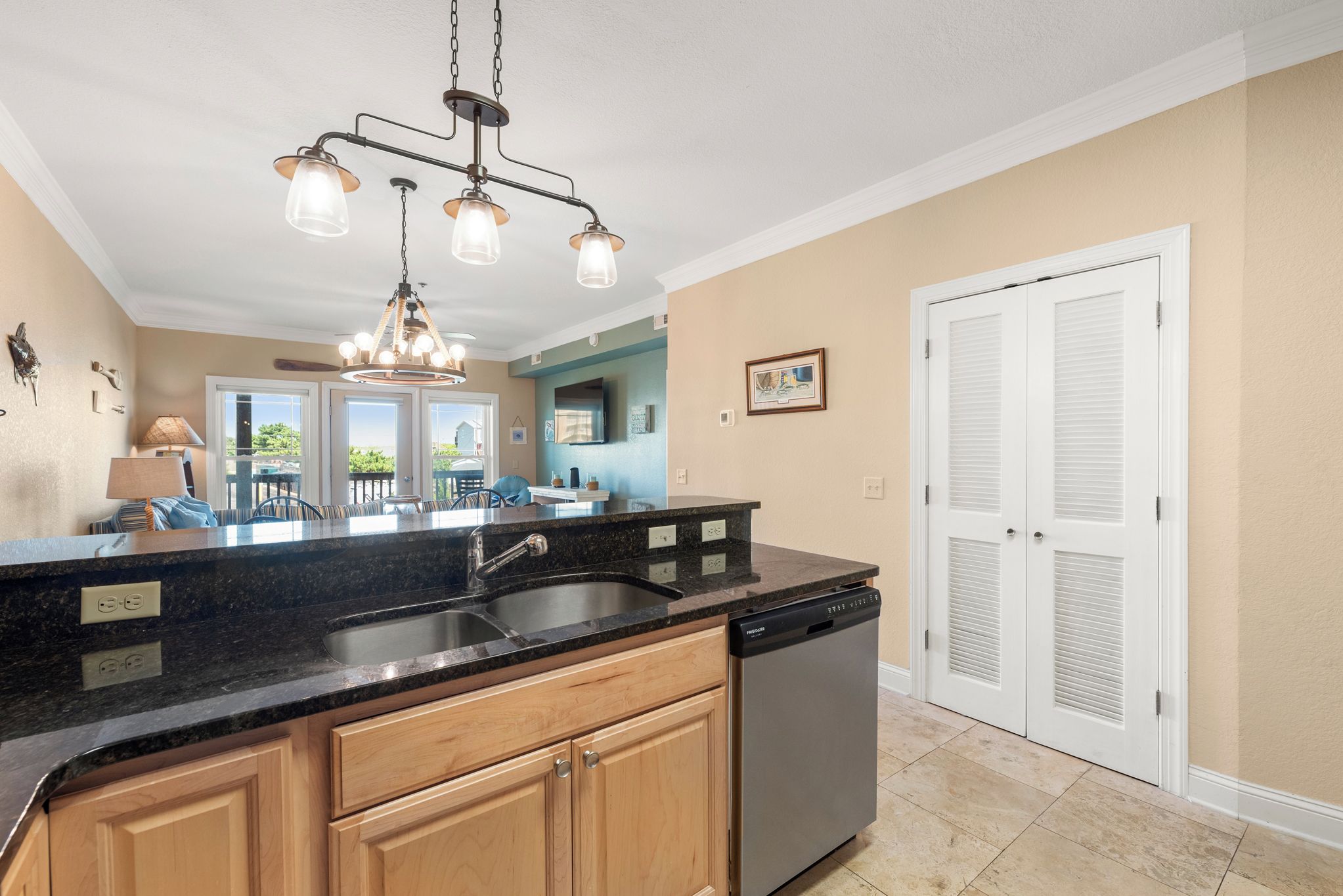 A kitchen with a central island, double sink, and a dishwasher.
