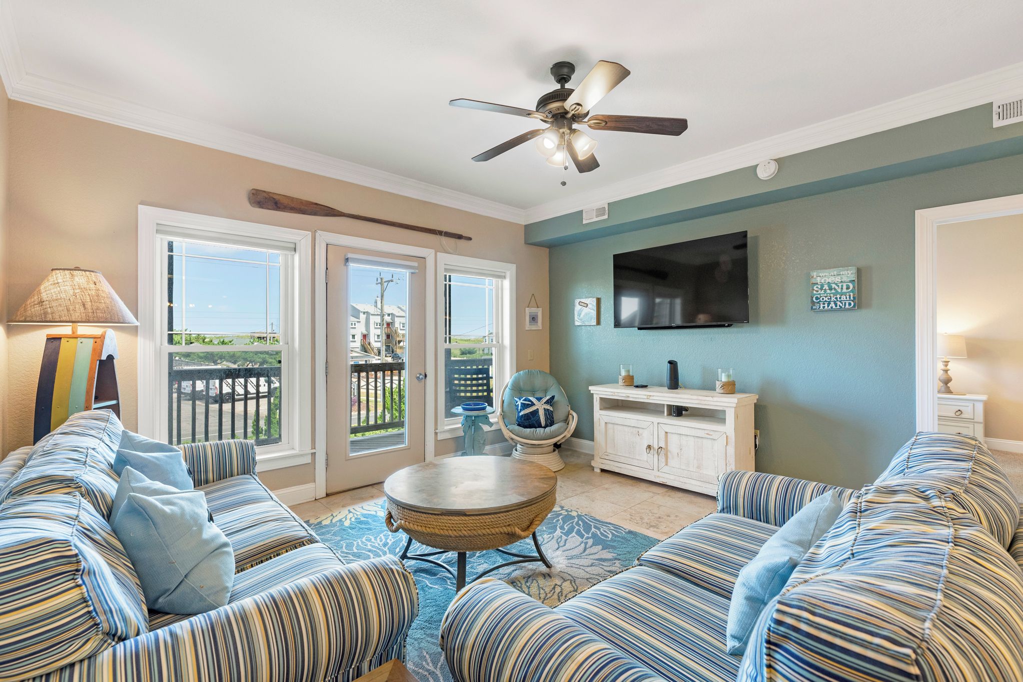 A living room with a sofa set, a round coffee table, a ceiling fan, and a television.