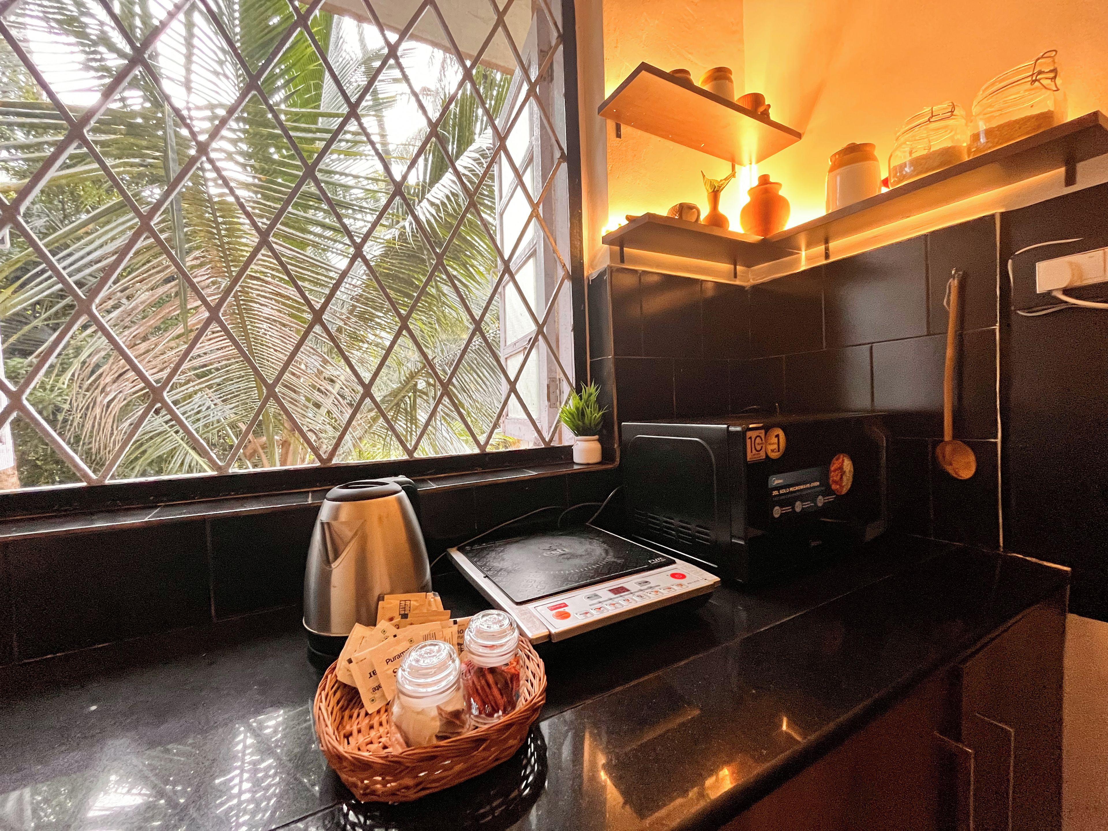 A kitchen with a black countertop, a toaster, a kettle, and a basket with jars.