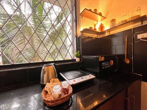 A kitchen with a black countertop, a toaster, a kettle, and a basket with jars. - 5 min walk to beach, 1 BHK Flat House in Candolim, fully equiped kitchen (Candolim)