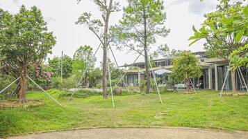 A residential area with multiple trees, a paved area, and a modern building with large windows.