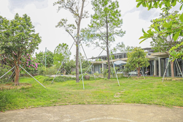A residential area with multiple trees, a paved area, and a modern building with large windows.