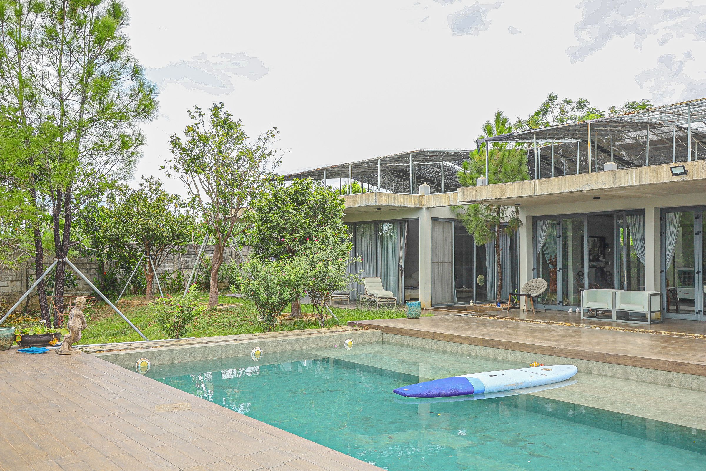 A modern house with a swimming pool, outdoor seating, and a garden.