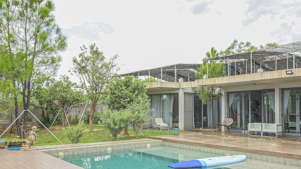 Une maison moderne dotée d’une piscine, d’un espace salon extérieur et d’un jardin.