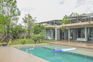 Una casa moderna con piscina, mobiliario exterior y jardín.