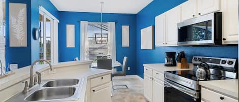A modern kitchen with blue walls, stainless steel appliances, and white cabinetry.