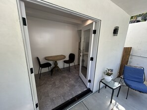 A room with a sliding glass door leading to an outdoor area, a small table with a chair, and a potted plant. - Peaceful Hilltop Escape in the Heart of LA Cozy (Los Angeles)