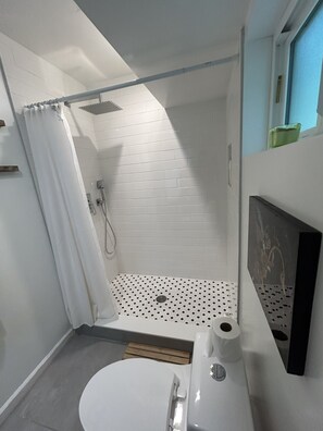 Et lille badeværelse med bruser, toilet og vask.