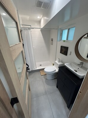 A bathroom with a toilet, sink, and shower area. - Peaceful Hilltop Escape in the Heart of LA Cozy (Los Angeles)