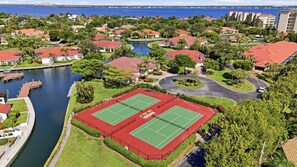 A residential area with a tennis court, a marina, and a body of water. - Waterfront Condo Minutes to Fort Myers Beach and Sanibel Island With Pool and Spa (Fort Myers)