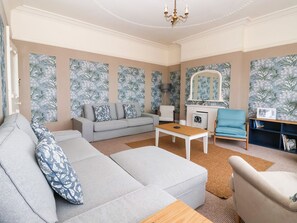 A modern living room with a grey sofa, a coffee table, a blue armchair, and a bookshelf. - Sunrise Lodge (Bridlington)