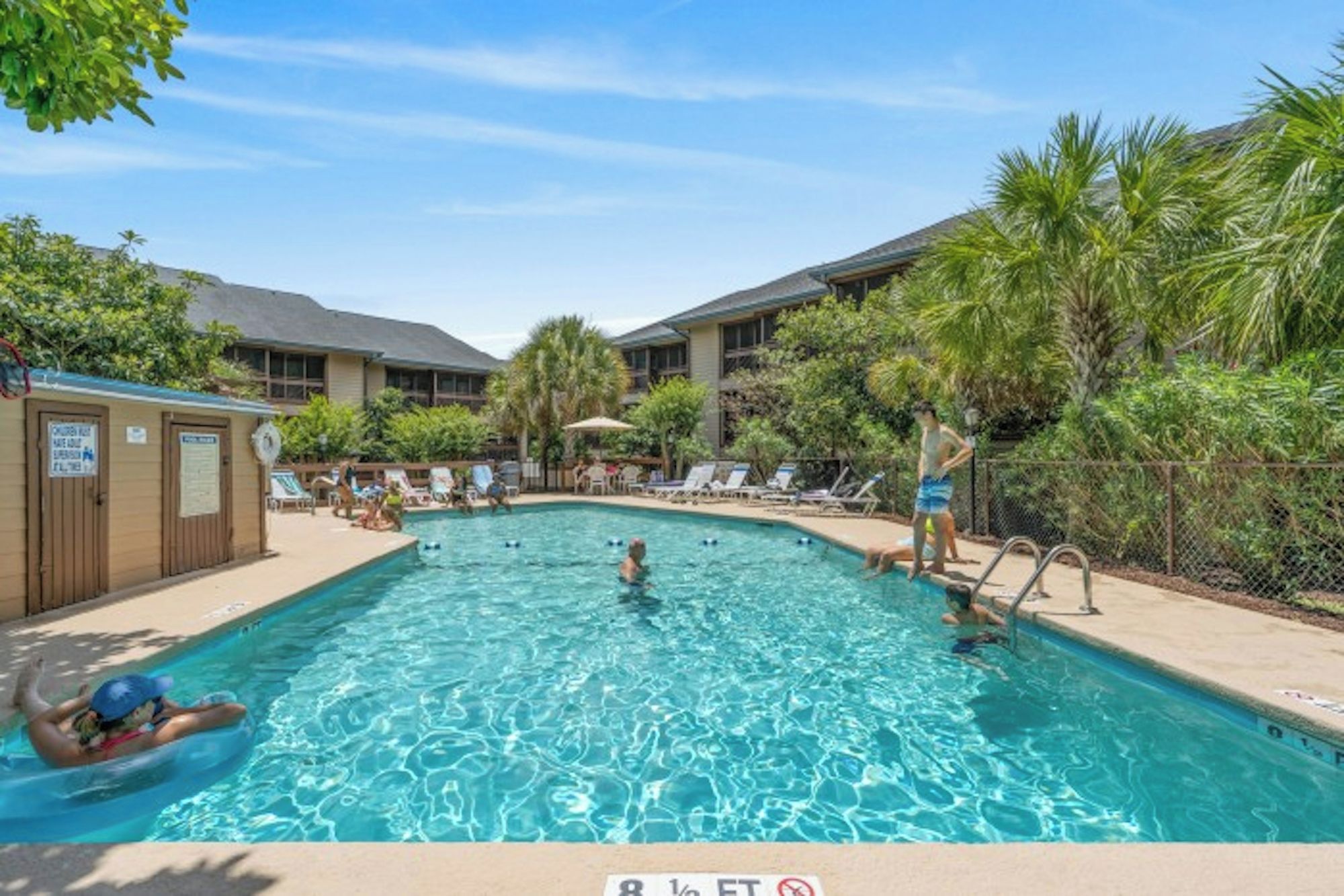 A swimming pool with lounge chairs and a lifeguard stand.