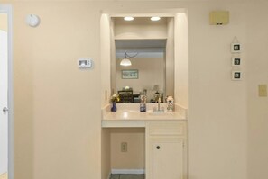 A bathroom with a vanity, mirror, and a small sink. - Pelican's Landing 208- 3BR in Shore Drive- Pool (Myrtle Beach)