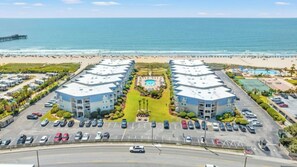 A beachfront hotel with a central pool, multiple parking lots, and a view of the ocean. - A Place at the Beach IV 216 Oceanfront 2BR- Pool (Myrtle Beach)