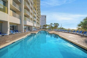 A swimming pool with lounge chairs and a hotel building in the background. - Bay Watch Resort 1610 -Efficiency-Great Amenities (North Myrtle Beach)