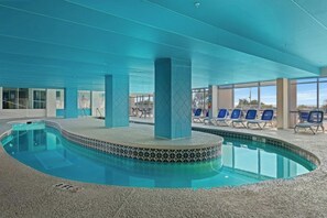 An indoor swimming pool with a tiled edge, lounge chairs, and a clear view of the outdoors. - Oceanfront 2BR/2BA -Bay Watch 1509- Great Balcony (North Myrtle Beach)