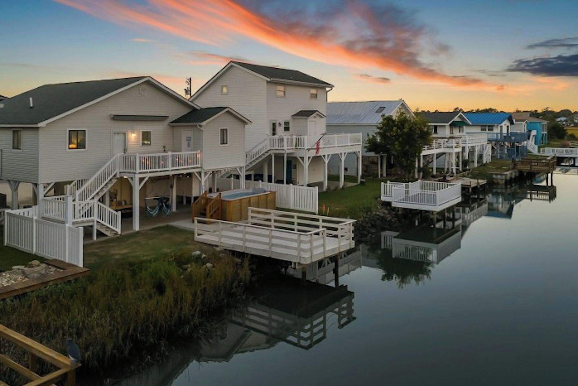 A waterfront property with multiple houses connected by walkways over water, featuring outdoor decks and a calm lake.
