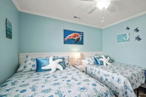 Ein Schlafzimmer mit zwei Betten, einem Deckenventilator und einer Wand mit einem Schildkrötengemälde.