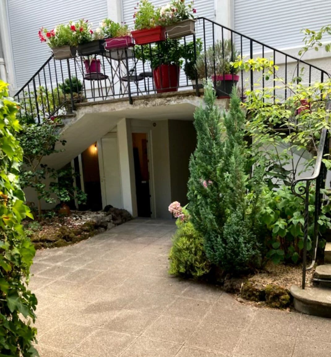 A covered outdoor staircase with potted plants and a stone pathway leading to a building entrance.