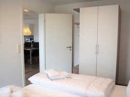 A bedroom with a bed, a wardrobe, and a desk with a chair.