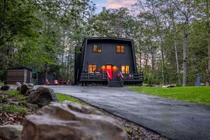 Ein modernes Blockhaus mit Veranda, umgeben von Bäumen.