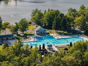 Complejo de piscinas con varias albercas, un área techada y un edificio con techo verde.