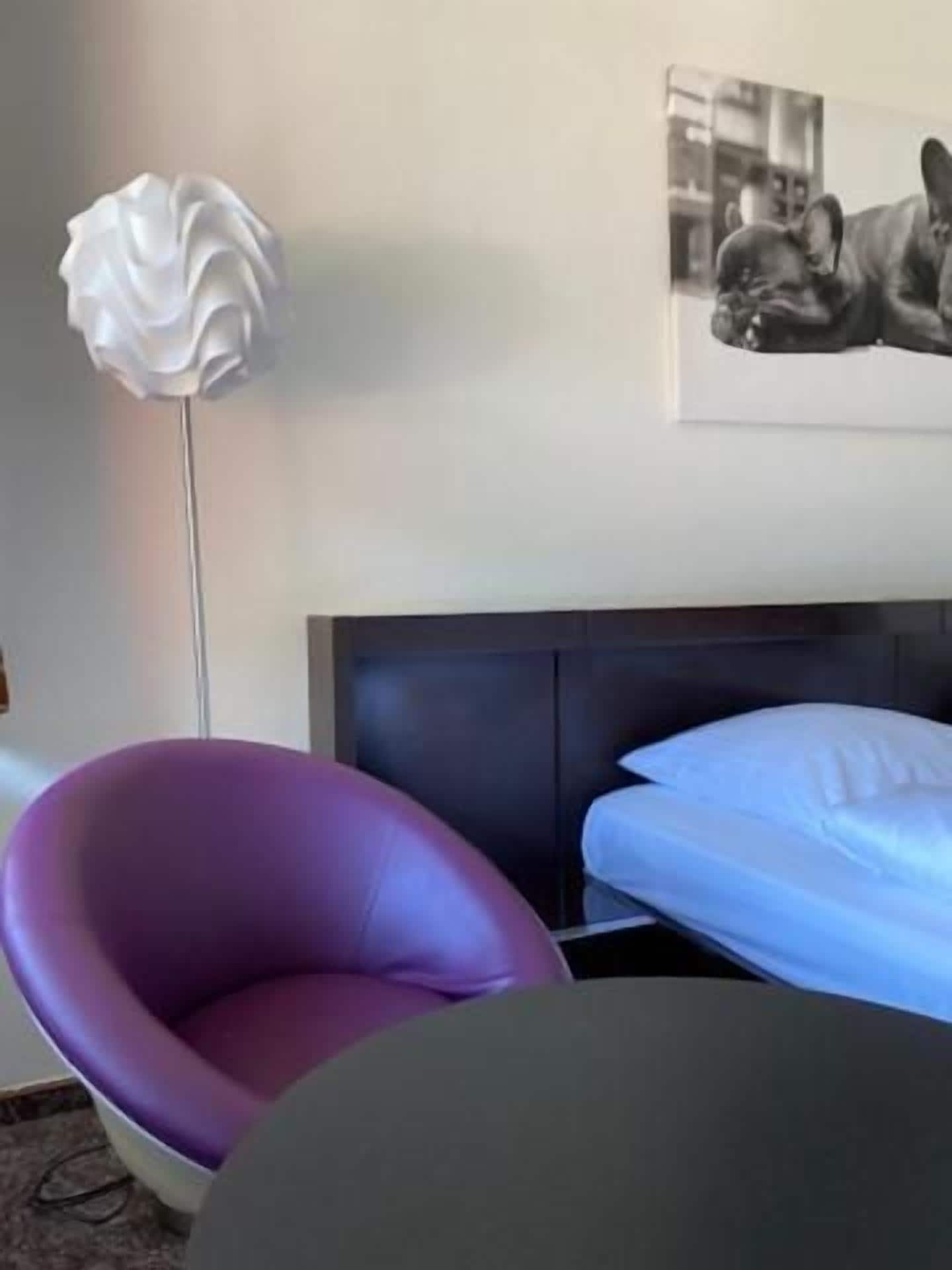 Una habitación con una cama, una silla y una lámpara de pie.