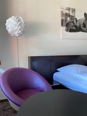 A room with a bed, a chair, and a floor lamp. - Hotel Tanneneck (Bad Bramstedt)