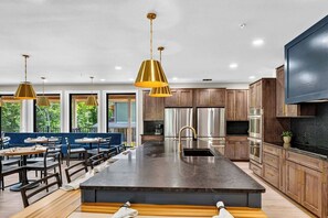 A modern kitchen with a central island, stainless steel appliances, and wooden cabinets. - Smoky Mountain Game Luxe Lodge (Gatlinburg)