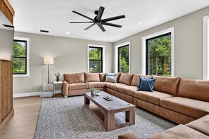 A modern living room with a sectional sofa, a coffee table, and a ceiling fan. - Smoky Mountain Game Luxe Lodge (Gatlinburg)